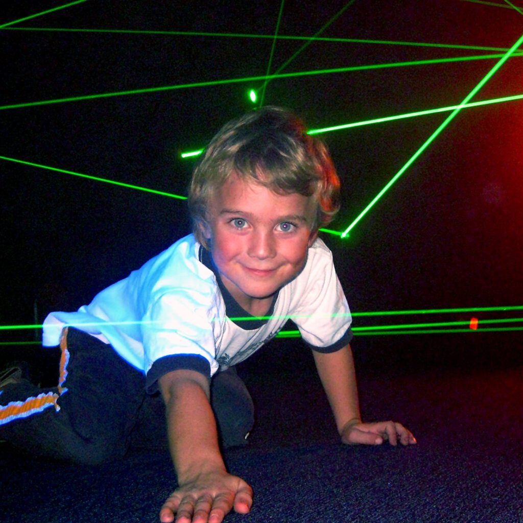 Young boy on hands and knees in laser maze.