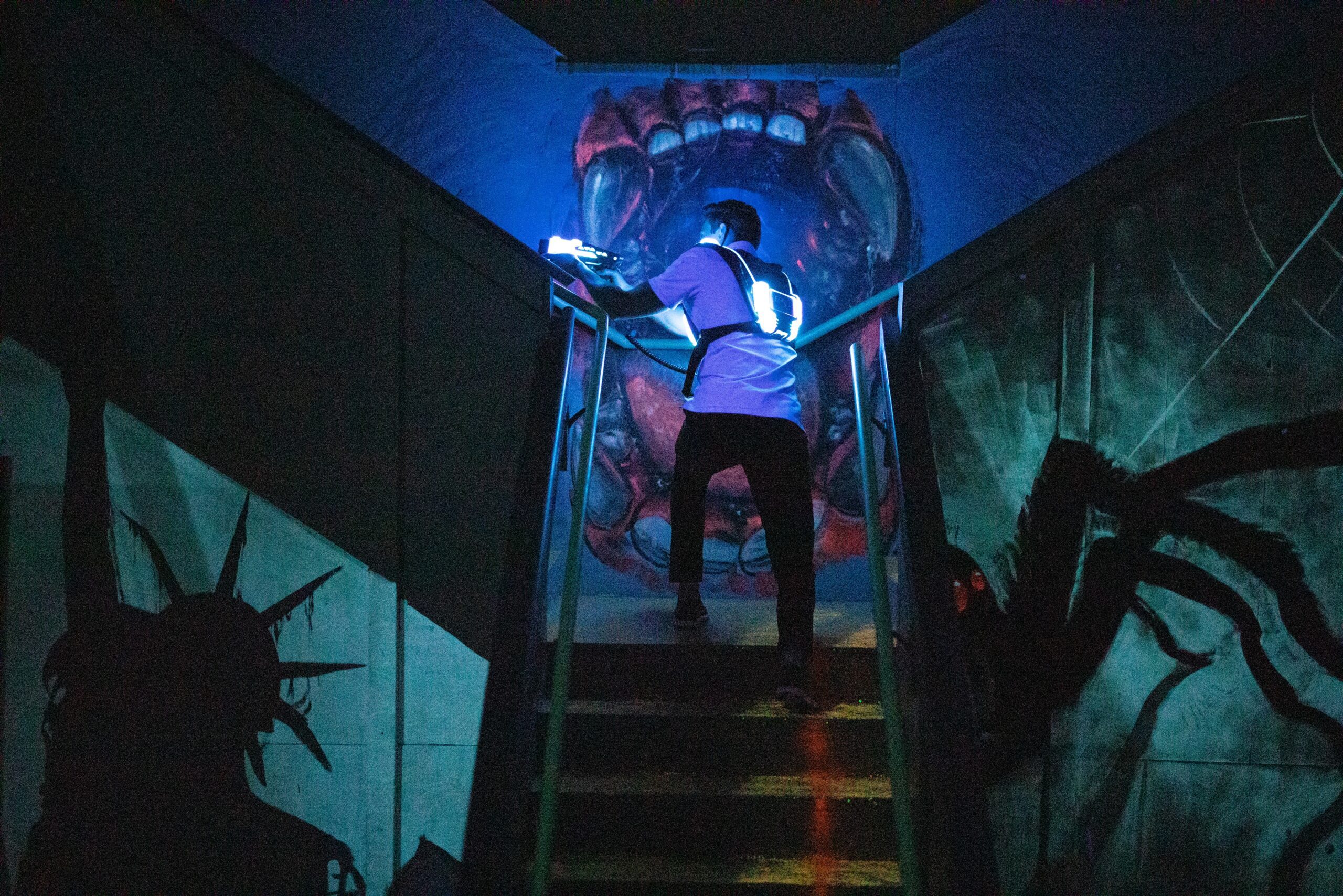 Dimly lit laser tag arena with player walking up a staircase.